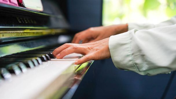 Adult woman plays electronic piano with note sheet. Professional pianist showing solo on acoustic black piano. practicing and learning how to play song. Classic instrument. - Fotoğraf, Görsel