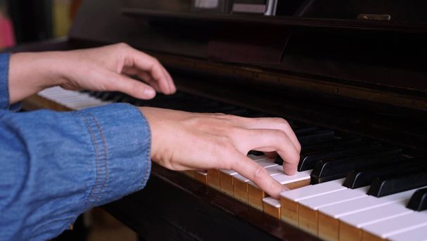 Professional pianist plays upright acoustic piano. Adult woman plays electronic piano with note sheet. Newby pianist practicing and learning how to play song. - Photo, Image