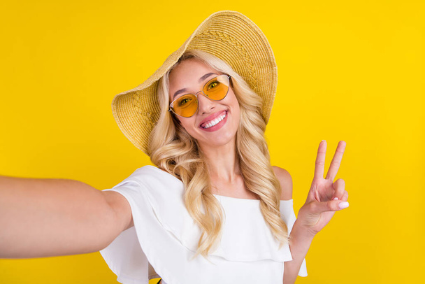 Self-portrait of gorgeous cheerful wavy-haired girl good mood showing v-sign isolated over bright yellow color background. - Foto, afbeelding
