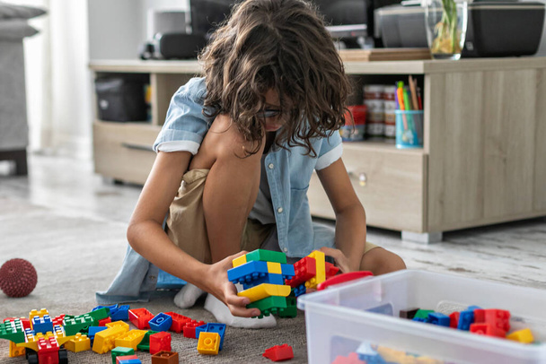 Kis csecsemő fiú játszik színes műanyag blokkok otthon nappali szőnyegen épület kreatív játék, képzelet - Fotó, kép