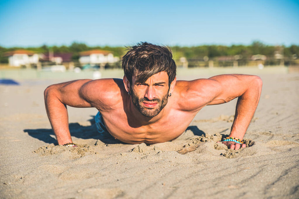 Primer plano retrato sexy de guapo modelo masculino en topless en la playa al amanecer - Hombre de fitness haciendo flexiones en la playa. Deportes y estilo de vida activo. - Foto, imagen