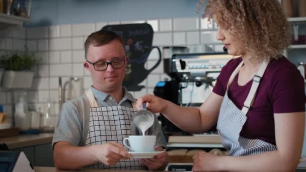 Белый мужчина с синдромом Дауна помогает официантке в приготовлении кофе. Съемка с красной гелиевой камерой в 8K. - Кадры, видео