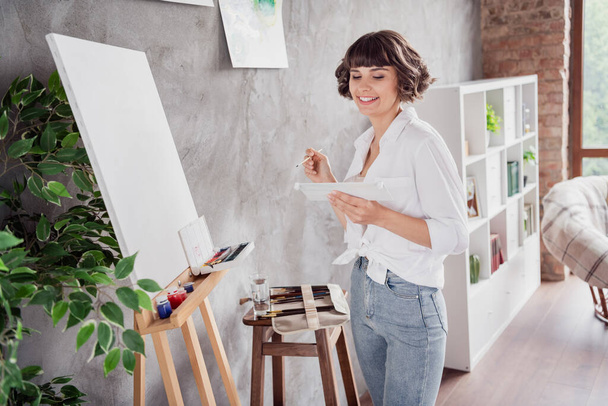 Photo portrait woman wearing white shirt creating painting spending free time at home. - 写真・画像