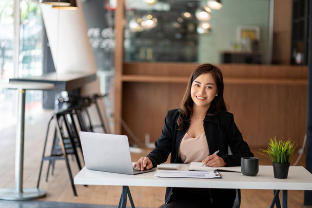 Modern ofiste dizüstü bilgisayar kullanan Asyalı iş kadını finansal grafikler ve emlak yatırım verileriyle bir hesap analizi raporu hazırlıyor. finansal ve vergi sistemi kavramları - Fotoğraf, Görsel