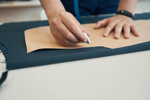 Käsi suunnittelija omistaa liitu, jonka tarkoituksena on piirtää ääriviivat kankaalle mukaan paperin mallin - Valokuva, kuva