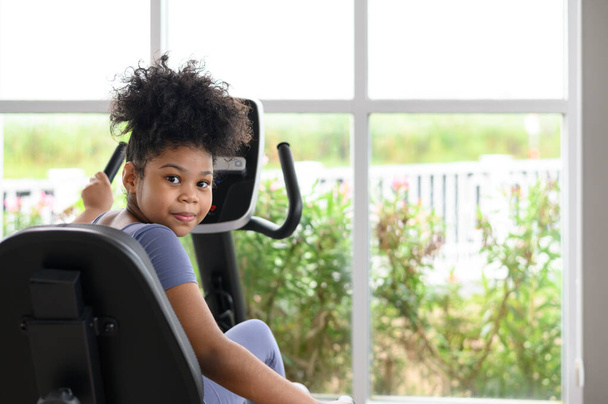 Πορτρέτο της ευτυχισμένης Αφρο-Αμερικανίδας σε γυμναστήριο. Αθλητισμός, υγιεινός τρόπος ζωής, δραστήρια παιδική ηλικία. Κοίτα την κάμερα. - Φωτογραφία, εικόνα