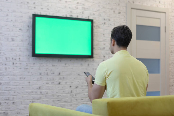Man sitting on the couch and watching tv. Green screen concept - Photo, image