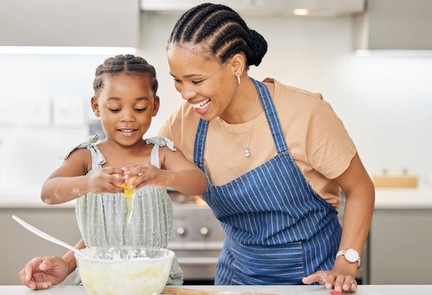 Foto de una atractiva madre joven vinculándose con su hija y ayudándola a hornear en la cocina en casa. - Foto, Imagen