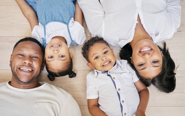 Happy mixed race family with two children lying on floor together and bonding at home from above. Little brother and sister spending time with their parents. - Photo, Image