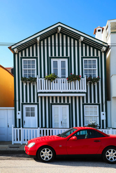 Typische Häuser an der Costa Nova, Aveiro, Portugal. Ein rotes Auto parkt vor der Haustür - Foto, Bild