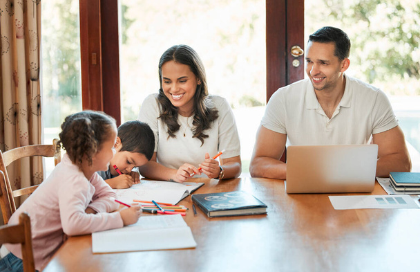 Молодая счастливая смешанная расовая семья сидит за столом вместе дома. Латиноамериканец работает над ноутбуком, пока его дети рисуют. Заботливая мать помогает своему маленькому сыну и дочери с домашней работой. - Фото, изображение