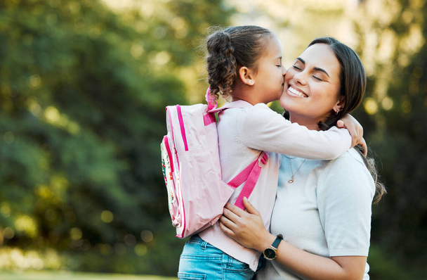 Little girl kissing her mother. Young mother hugging her daughter. Loving mother hugging daughter before school outside. Little girl going to school. Happy woman embracing daughter. - Foto, Bild