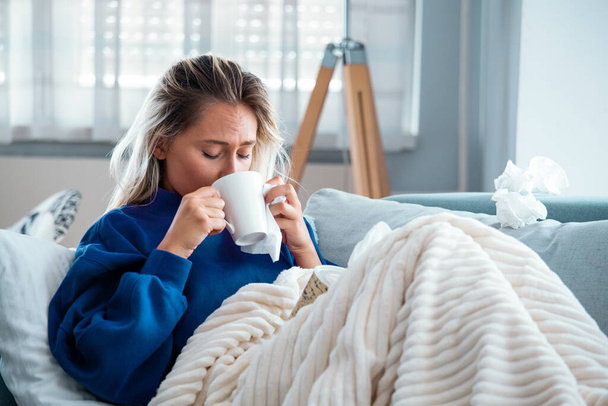 Cold And Flu. Portrait Of Ill Woman Caught Cold, Feeling Sick And drinking hot bevarage. Closeup Of Beautiful Unhealthy Girl Covered In Blanket Wiping Nose. Healthcare Concept. - Photo, Image