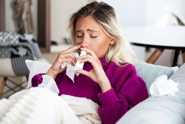 Frau hat Grippe und benutzt Nasenspray, um sich selbst zu helfen. Frau mit Nasenspray. Nasenspray gegen Erkältung. Krank mit Schnupfen Frau tropft Nase. Frau verabreicht Nasenspray - Foto, Bild