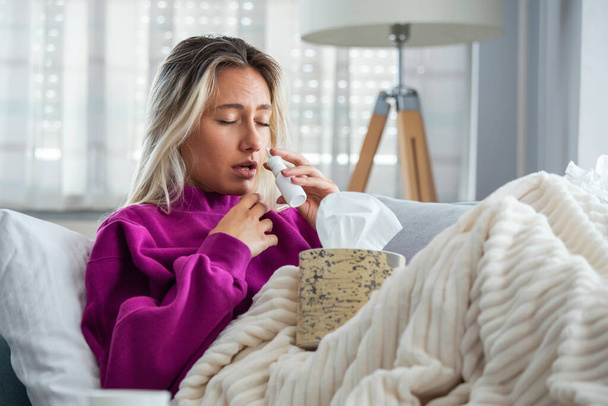 Woman is having flu and she is using nasal spray to help herself. Woman using nasal spray. Nasal spray to help a cold. Sick with a rhinitis woman dripping nose. Woman applies nasal spray - Foto, immagini