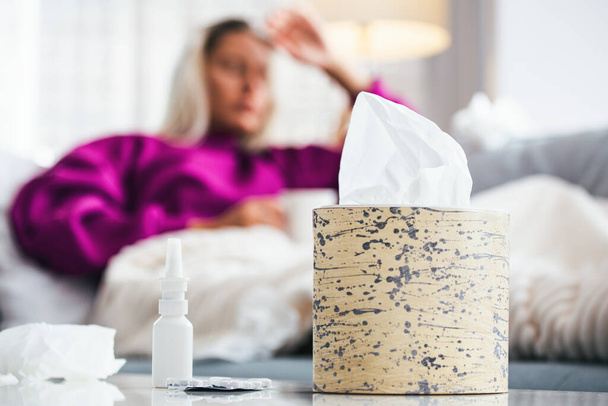 Erkältung und Grippe. Porträt einer erkälteten Frau, die sich krank fühlt und in Papiertücher niest. Nahaufnahme eines schönen ungesunden Mädchens, das in eine Decke gehüllt die Nase wischt. Gesundheitskonzept. hohe Auflösung - Foto, Bild