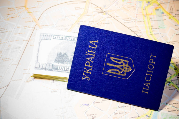 Pasaporte ucraniano con billetes se encuentra en el mapa. Salida de refugiados debido a la guerra en Ucrania - Foto, imagen