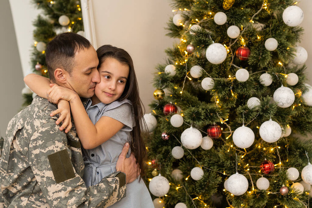 Soldier in uniform with his daughter. An off duty military man spending Christmas holiday with his family at home - Foto, Imagen