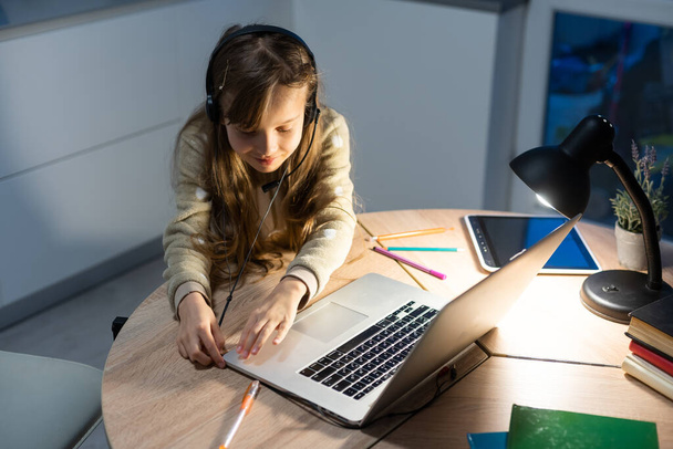 Bağlantı iyi. Seni duyabiliyorum. Küçük kız rahat masa başı çalışma uzaktan bilgisayarla internet üzerinden öğretmenlerle iletişim kurma ev içinde kulaklık var. - Fotoğraf, Görsel