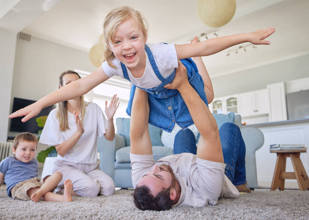Portrait of a happy caucasian family of four having fun while being playful on the lounge floor carpet at home. Young positive couple with two smiling chidren playing a game at in a bright lounge. - Photo, Image