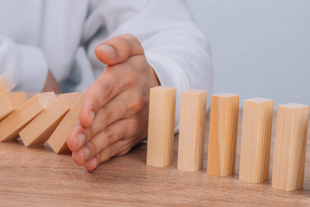 hand stops falling dominoes or wooden puzzle - Foto, Bild