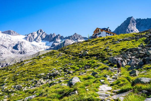 Two hikers ascending Planauer Hut on sunny summer day. Zillertal Alps, Austria - 写真・画像