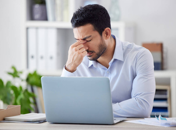 Stressed asian businessman working on laptop. Frustrated professional stressed while working online. Anxious man searching for solution while suffering from a bad headache against bright copyspace. - Photo, image