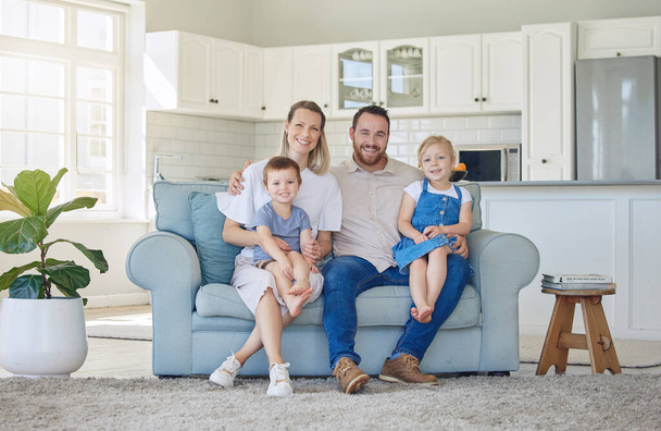 Happy and cheerful caucasian family of four smiling while relaxing together at home. Carefree loving parents bonding with their cute little son and daughter. Siblings sitting with their mom and dad. - Photo, image