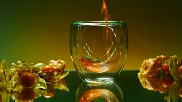 Zbliżenie wlanie soku jabłkowego do szklanki stojącej na szklanym stole powierzchniowym. Spinacz. Jagody na stole, koncepcja zdrowej diety i witamin  - Materiał filmowy, wideo
