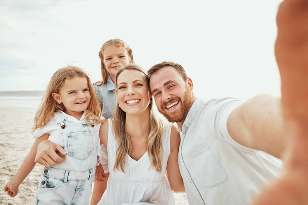 Vrolijke Kaukasische familie neemt selfie samen op het strand. Knappe man op zoek gelukkig terwijl het nemen van foto met zijn vrouw en twee dochters terwijl op vakantie. - Foto, afbeelding