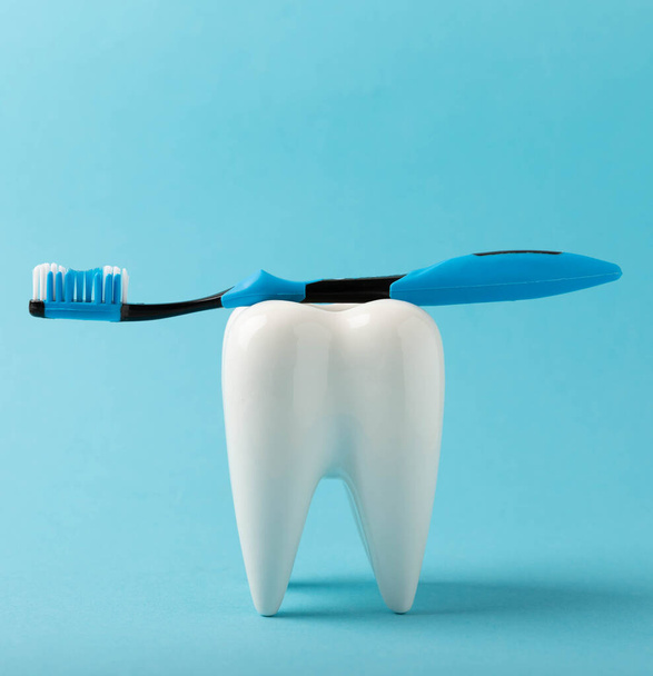 Reinigungsmodell eines weißen Zahnes mit einer Zahnbürste auf blauem Hintergrund. Das Konzept der Zahnhygiene. Prävention von Plaque und Zahnfleischerkrankungen. MOCKUP - Foto, Bild