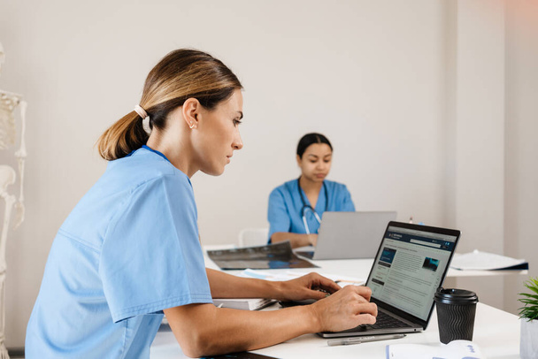 Multiracial women doctors working with laptops in office indoors - Foto, Bild
