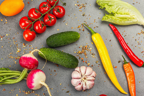 Koken ingrediënten achtergrond. Specerijen, groenten, knoflook, gekleurde pepers chili, en komkommers. Steenbeton achtergrond, bereiding food concept, plat lay, bovenaanzicht - Foto, afbeelding