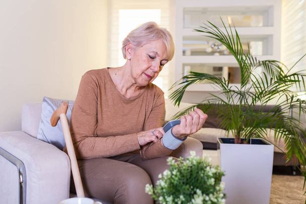 Blutdruckmessung zu Hause. Blutdruckspiegel zu Hause überprüfen. Seniorin überprüft Blutdruckwerte zu Hause - Foto, Bild