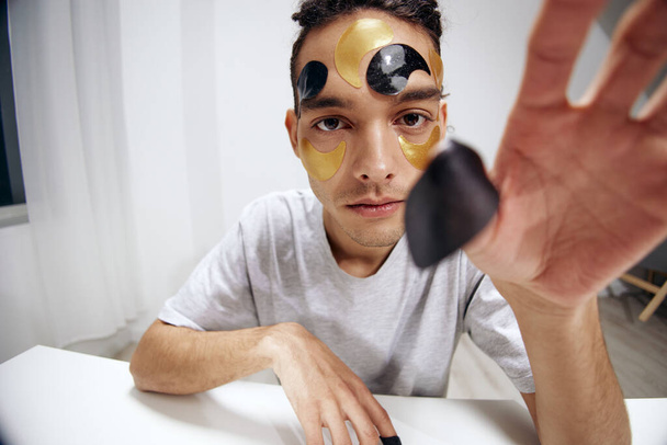 Ein junger Mann schwarz-goldene Flecken auf dem Gesicht Gesundheit Kosmetologie isolierten Hintergrund. Hochwertiges Foto - Foto, Bild