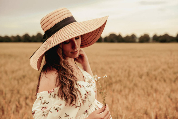 Mulher campo de trigo natureza. Jovem feliz de chapéu de sol no campo de trigo de verão ao pôr-do-sol. Espaço de cópia, pôr do sol, luz de sinalização, estação de verão. Boho estilo chique - Foto, Imagem