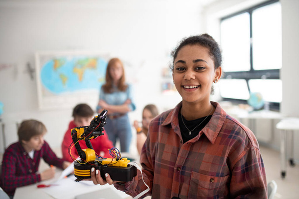 A college student holding her robotic toy at robotics classroom at school. - Foto, imagen