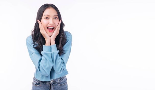 Surprise excited asian woman casual screaming mouth wow promotion discount product holding hands under chin standing copy space over isolated white background. Happy young girl shocked shopping sale. - Zdjęcie, obraz