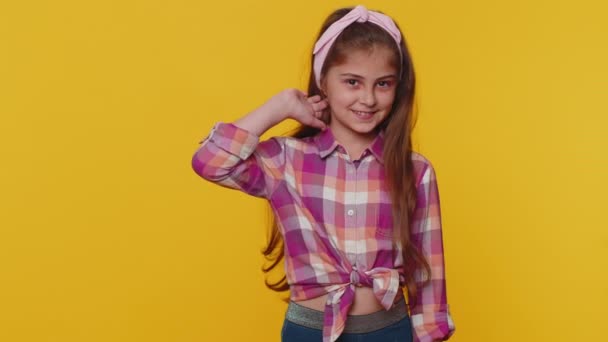 Cheerful lovely young preteen child girl kid smiling, looking at camera. Little funny toddler children schoolgirl isolated portrait alone on studio yellow background. Female nature beauty. Childhood - Materiał filmowy, wideo