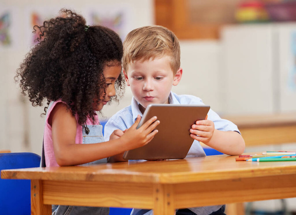 Φωτογραφία δύο μαθητών προσχολικής ηλικίας που κοιτούν κάτι σε μια ψηφιακή ταμπλέτα μαζί.. - Φωτογραφία, εικόνα