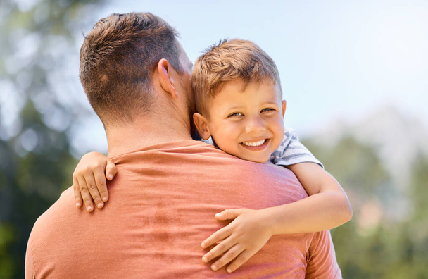 Retrato de un niño pequeño abrazando a su padre al aire libre. - Foto, imagen