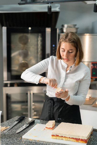 young girl chef makes desserts. bakes sweets and cakes. makes blanks and prepares fruits for the filling. baking, dessert, sweets, complex cooking processes. - Foto, Bild