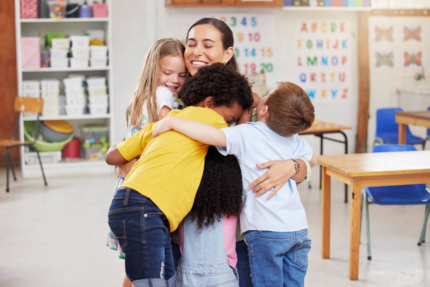 Fotografía de una mujer abrazando a sus alumnos. - Foto, Imagen