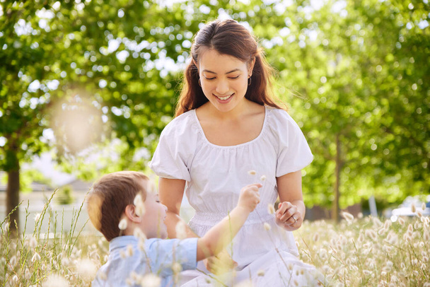 Shot of a young mother and son picking flowers in nature. - 写真・画像