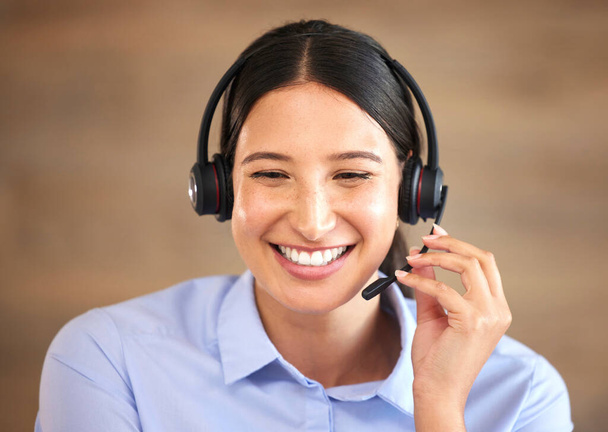 Closeup of smiling mixed race call centre agent talking to customers with a headset. Hispanic businesswoman answering calls, helping clients from an office. Headshot of customer service representative - Foto, afbeelding