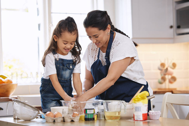 Girato di una madre e la sua giovane figlia cuocere insieme a casa. - Foto, immagini