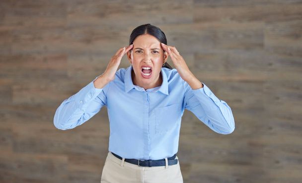 Young mixed race woman looking angry and annoyed while screaming and expressing rage at work. Hispanic female having a mental breakdown while standing in an office against a copyspace wall. - Foto, Bild