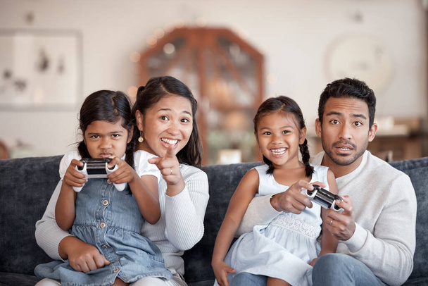 Retrato recortado de una afectuosa familia joven de cuatro niños jugando videojuegos en la sala de estar en casa. - Foto, Imagen