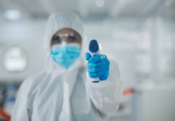 Fotografía de un joven científico sosteniendo un termómetro en un laboratorio. - Foto, Imagen