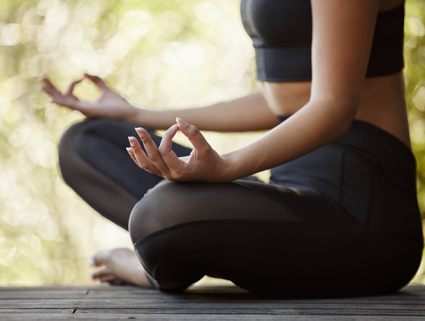 Przycięte ujęcie nierozpoznawalnej młodej kobiety, która medytuje podczas jogi na świeżym powietrzu. - Zdjęcie, obraz